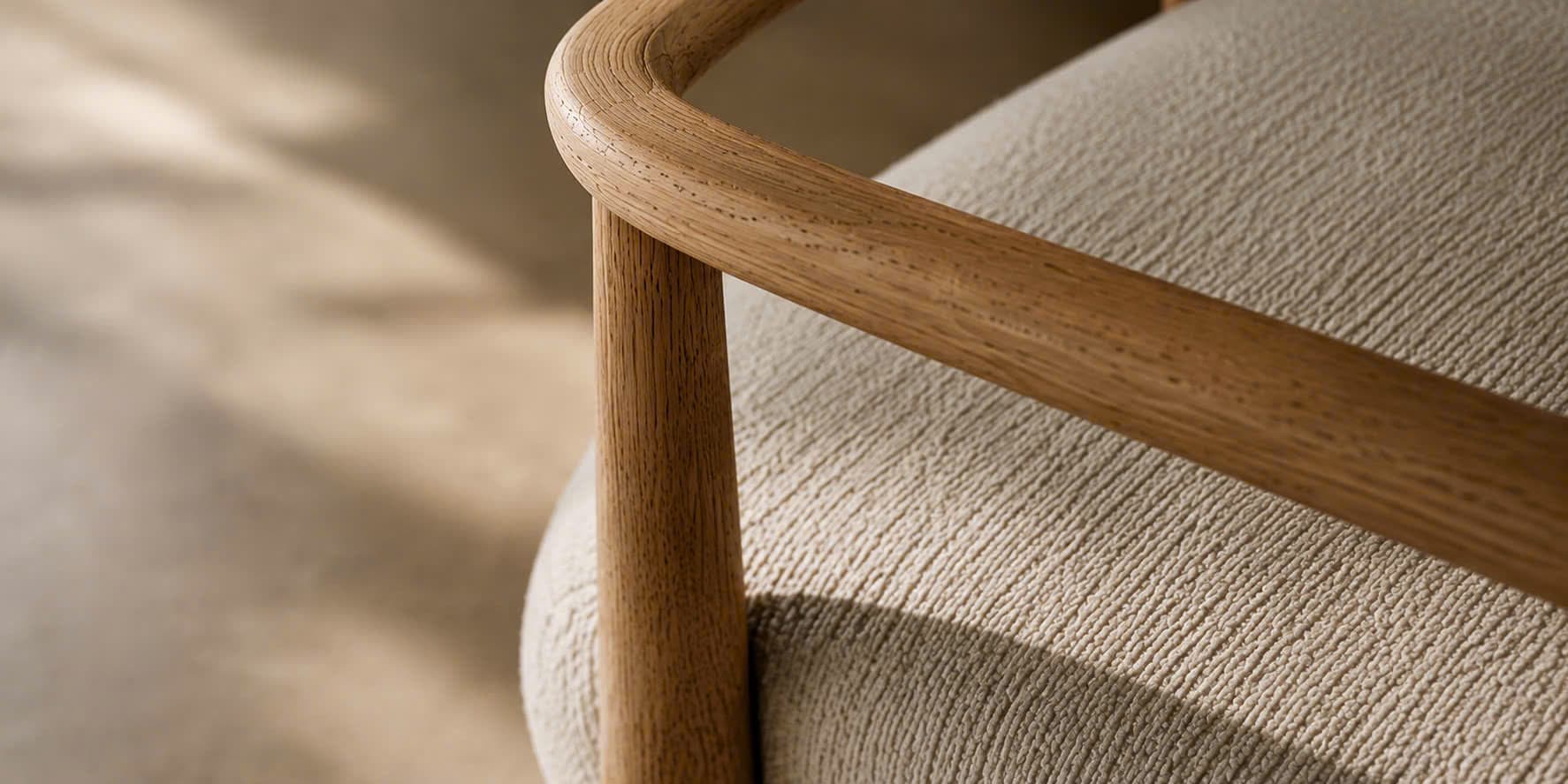 A handcrafted oak chair frame wrapped in soft bouclé, held in warm afternoon light