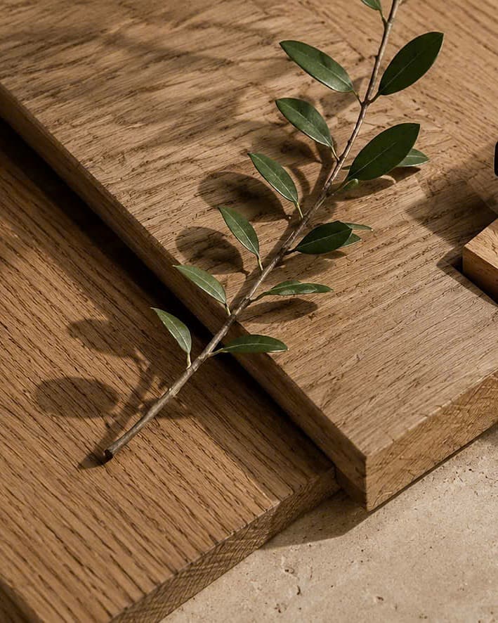 Solid white oak boards showing their open grain beside a green sprig